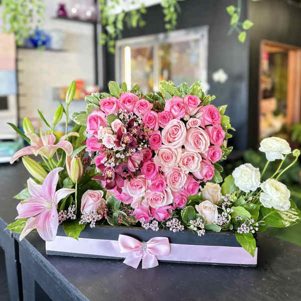 Pink rose arrangement with lilies in a rectangular box