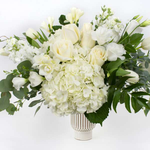 White roses and hydrangeas arranged in a clear vase