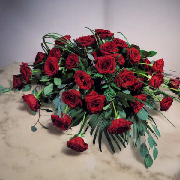 Low, elongated arrangement of red roses spread across a marble surface
