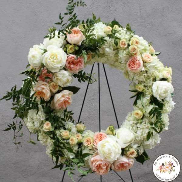 Standing wreath of white and peach roses and hydrangeas on a metal easel