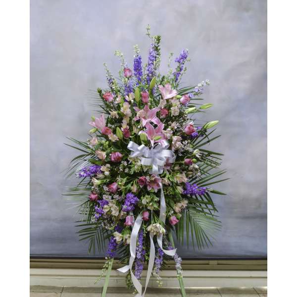 Tall standing floral spray with pink lilies and purple blooms, tied with white ribbon