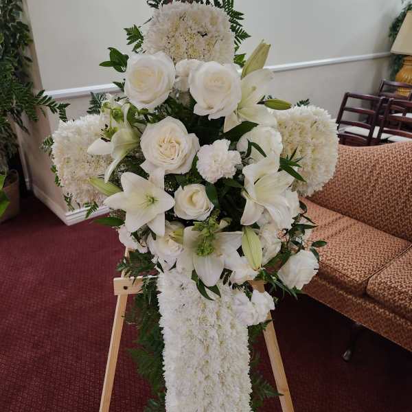 White funeral spray with roses, lilies, and chrysanthemums on an easel