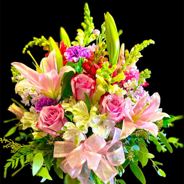 Pink roses and lilies in a glass vase with a pink ribbon