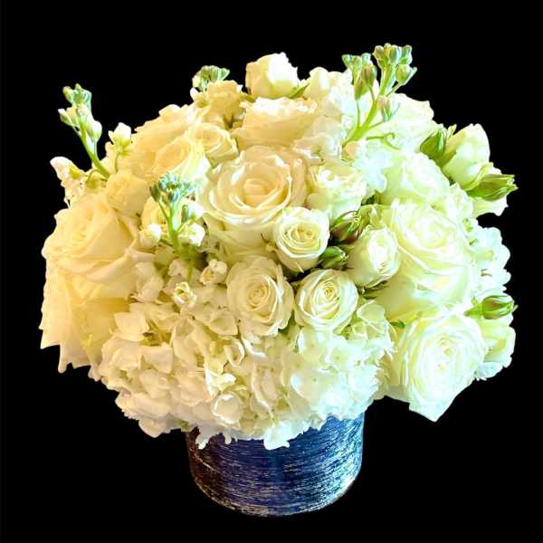 White rose and hydrangea arrangement in a blue textured vase
