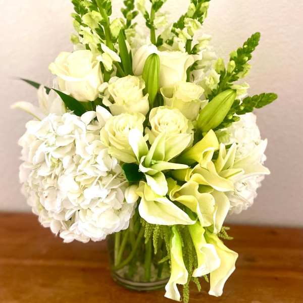 White and pale green floral arrangement in a glass vase