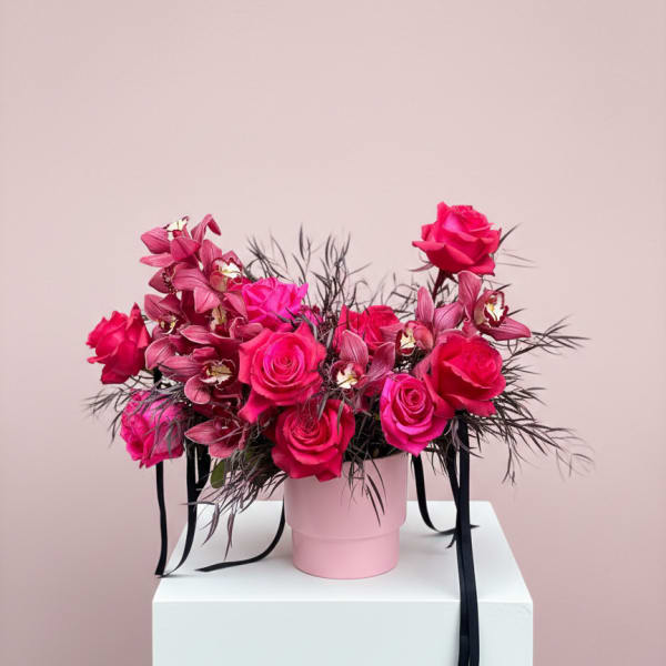 Pink roses and orchids in a pink hat box with black ribbon