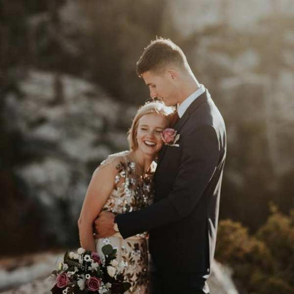 Couple embracing, with the woman holding a bouquet of pink and white flowers