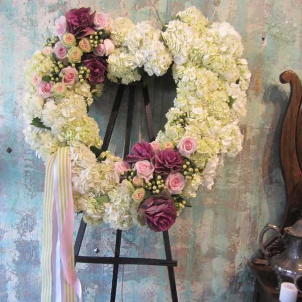 Heart-shaped floral wreath on an easel with pink and white flowers