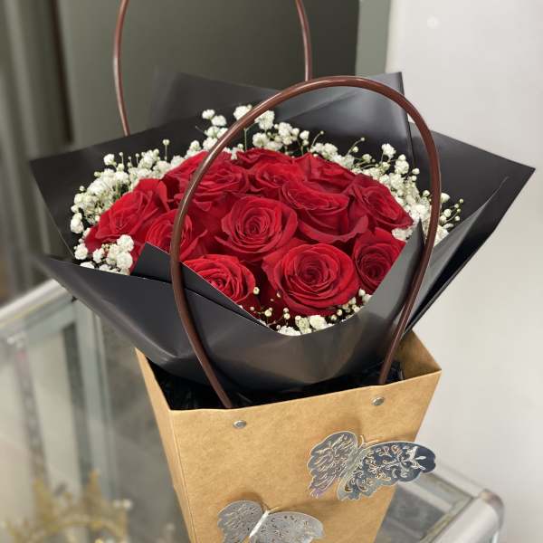 Red rose bouquet with baby's breath in a brown gift bag