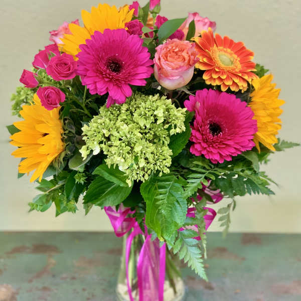 Bright mixed bouquet in a glass vase with pink, orange, and yellow blooms