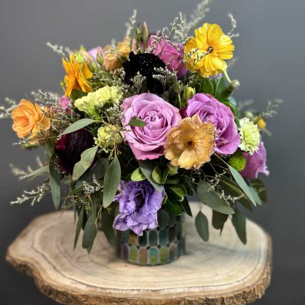 Mixed bouquet of roses and colorful blooms in a patterned vase