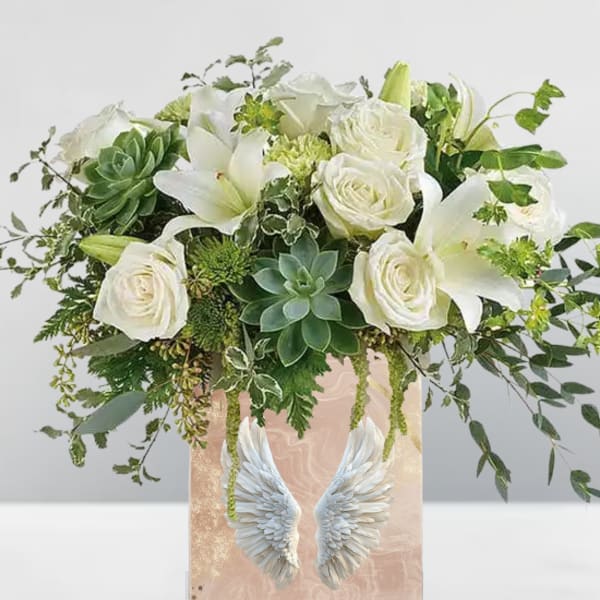 White roses and lilies in a pink vase with angel wings