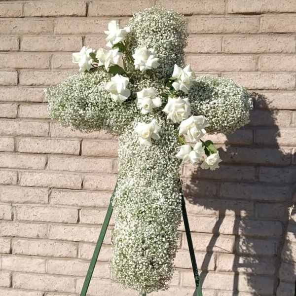 White floral cross on a stand with small white roses