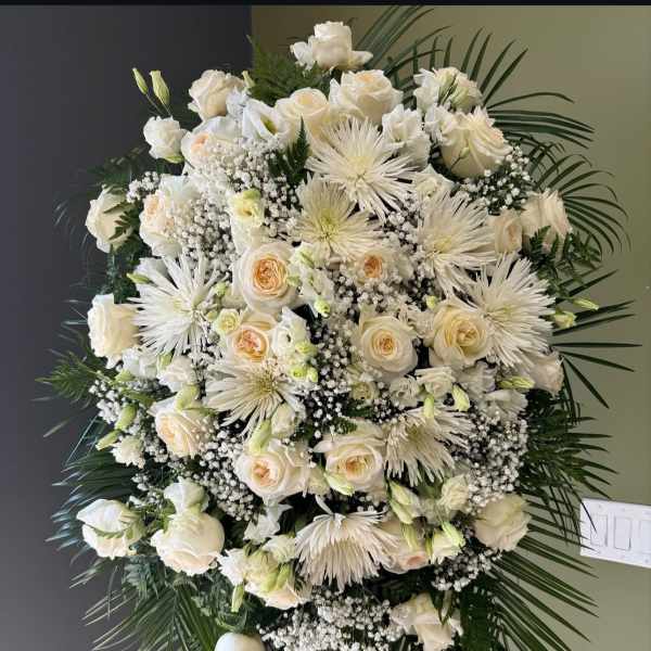 Large white funeral spray with roses and spider mums on a standing easel