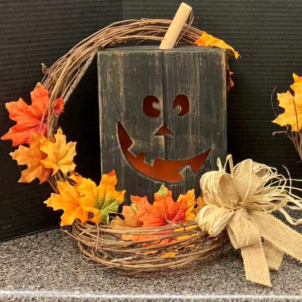 Halloween wreath with orange leaves and a jack-o'-lantern sign