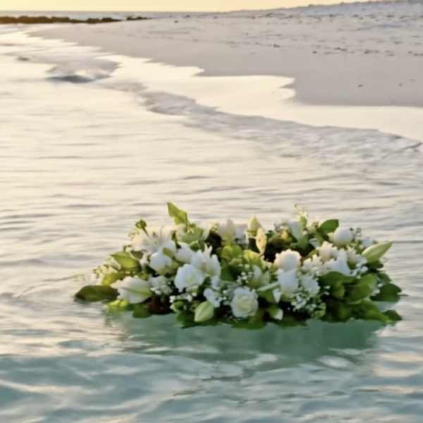 White floral arrangement floating on water at the beach