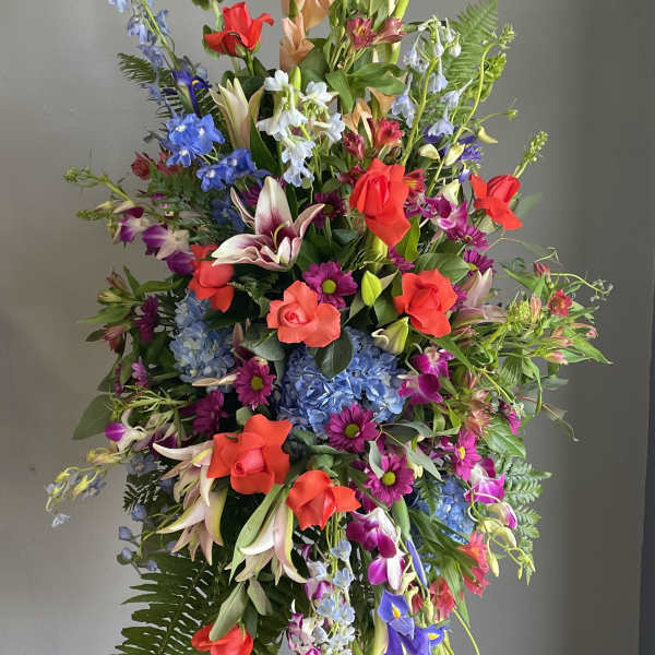 Tall mixed floral standing spray with red roses and blue flowers