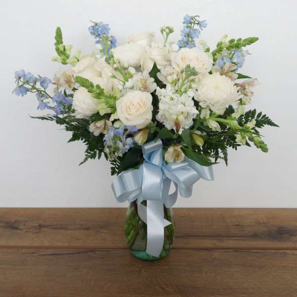 White and blue mixed bouquet in a glass vase with a pale blue ribbon