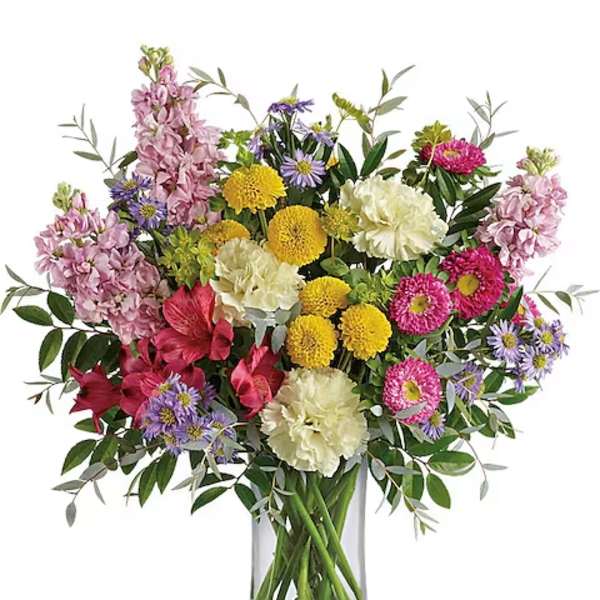 Mixed bouquet of pink, yellow, white, and purple flowers in a clear glass vase