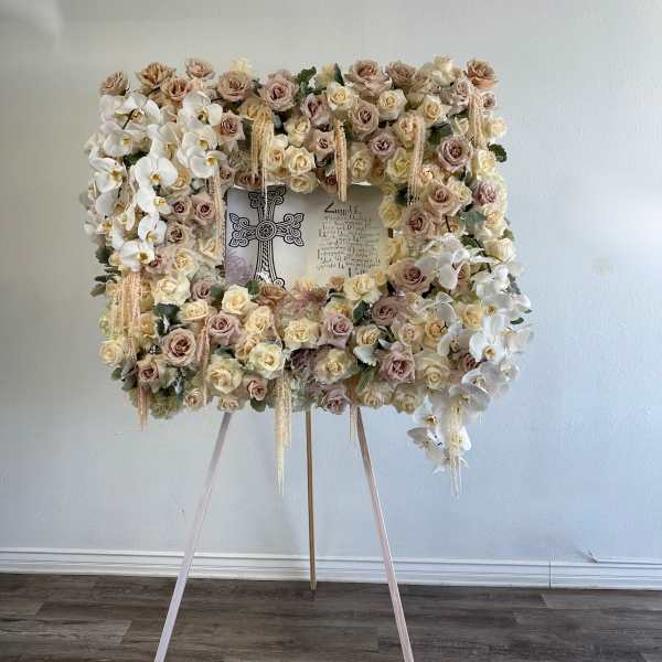 Floral standing easel with white orchids and blush roses around a framed tribute