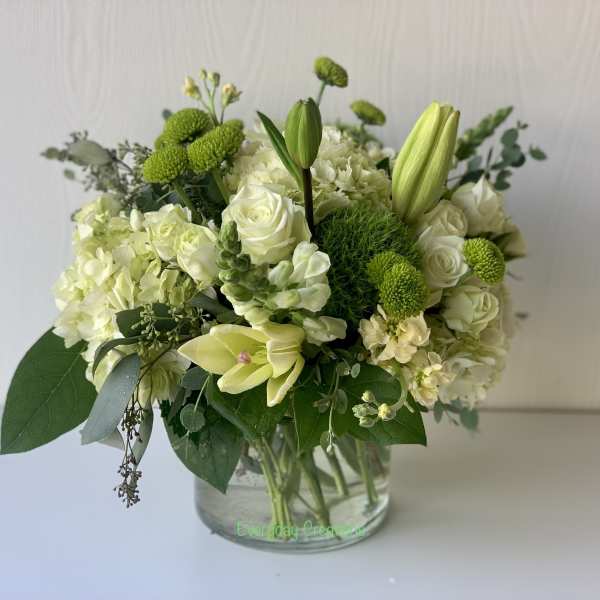 White and green floral arrangement in a clear glass vase