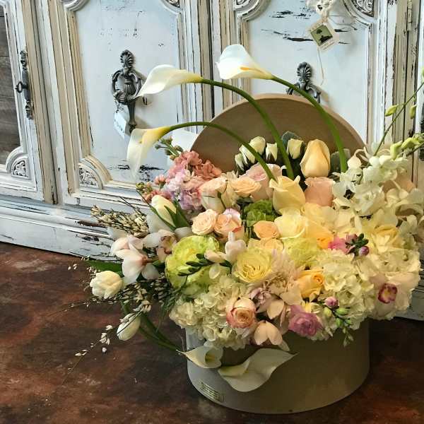 Pastel floral arrangement with white calla lilies and roses in a round box