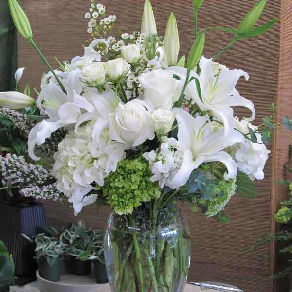 White lilies and roses arranged in a clear glass vase