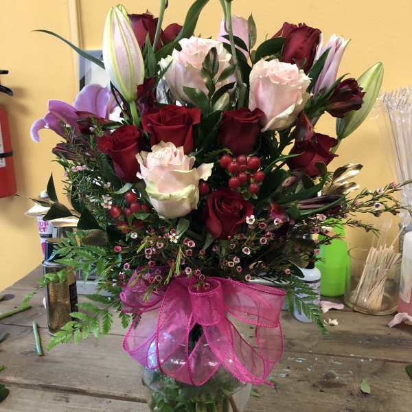 Mixed bouquet of red and pink roses with lilies in a glass vase