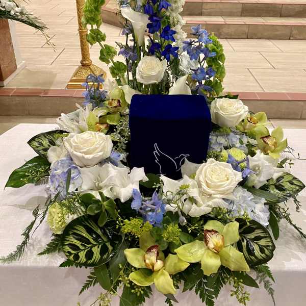 Large white and blue floral arrangement around a dark blue urn
