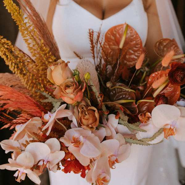 Bride holding a bouquet of peach and white flowers with dried accents