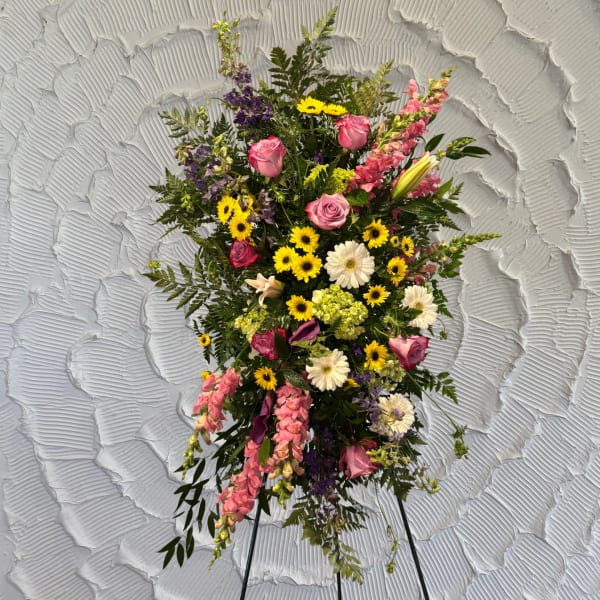 Standing floral spray with pink roses, yellow daisies, and purple blooms