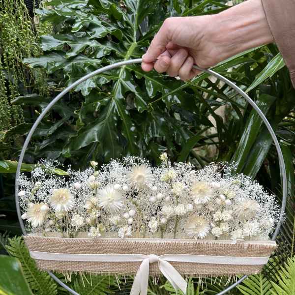 White floral arrangement in a round metal hoop with a ribbon-tied burlap wrap