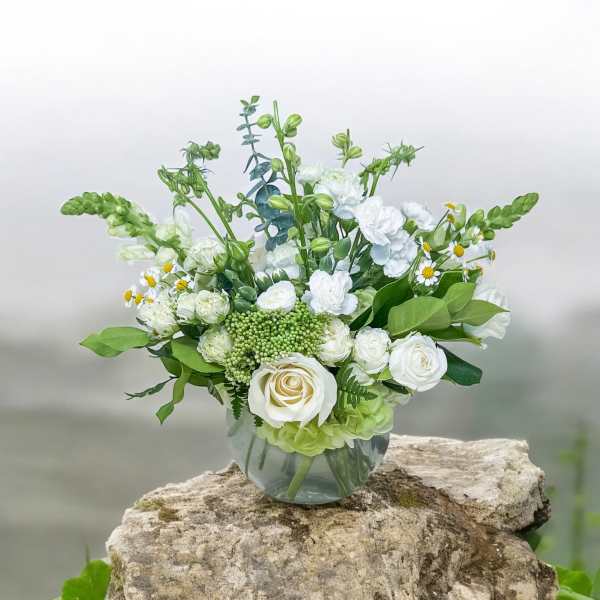 White and green floral arrangement in a clear glass vase