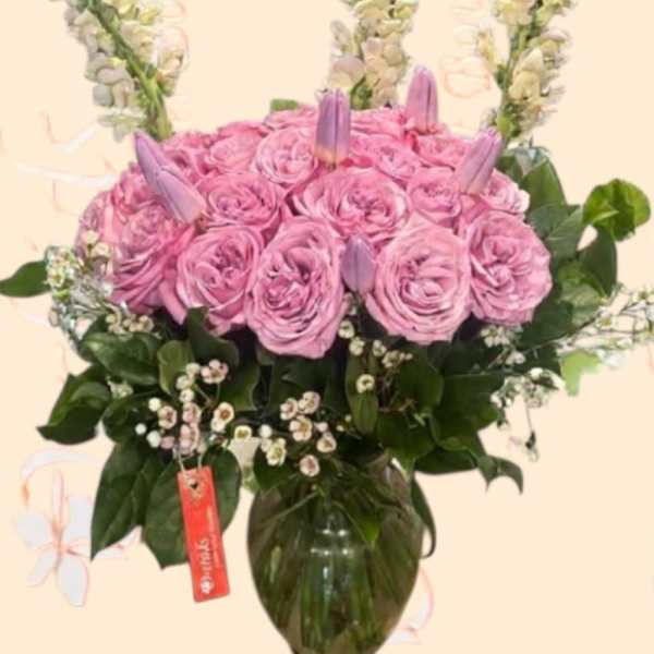 Pink rose arrangement in a glass vase with tall white flower spikes