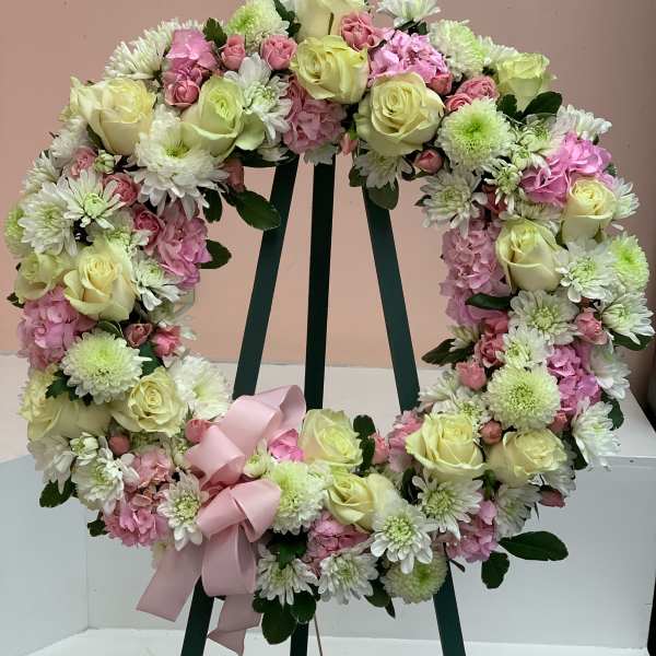 Heart-shaped floral wreath with pale roses, pink blooms, and a pink ribbon