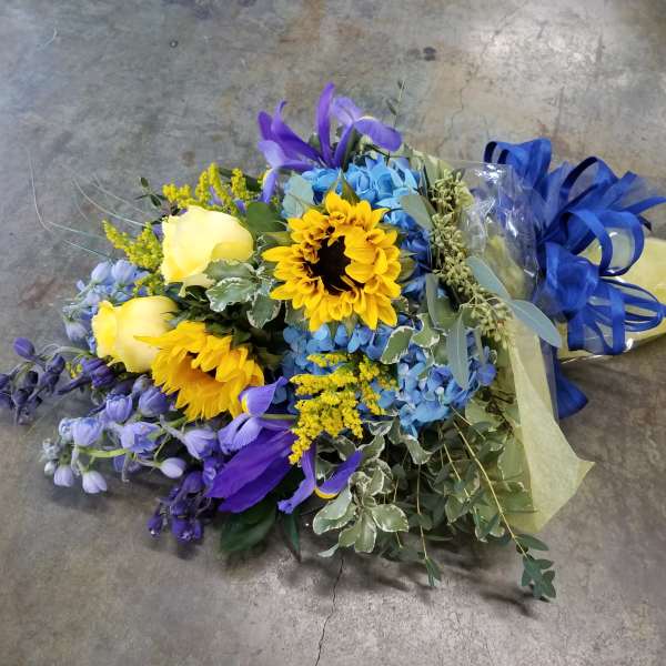 Bouquet of yellow roses, sunflowers, and blue flowers tied with a blue ribbon