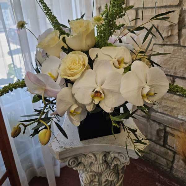 White orchids and cream roses arranged in a black vase
