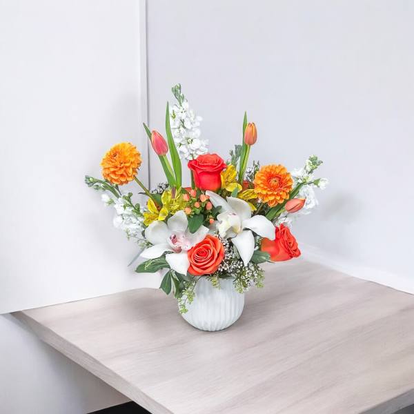 Mixed bouquet in a white vase with orange, red, and white flowers