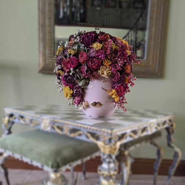 Pink vase with a dense arrangement of dried flowers and berries