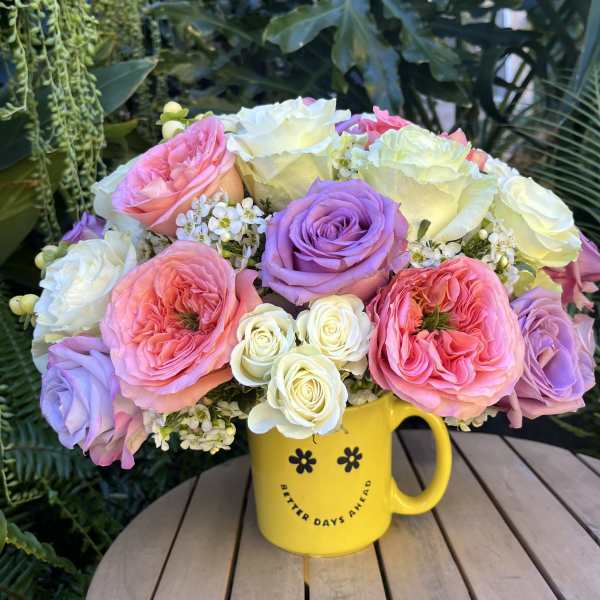 Pink, lavender, and white roses in a yellow mug vase