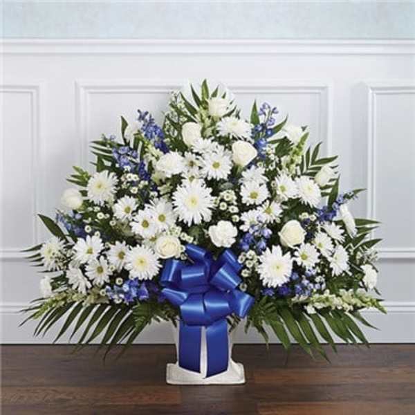 White and blue floral spray with a blue ribbon on a stand