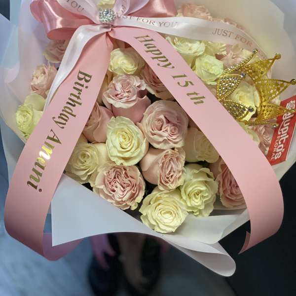 Pink and cream rose bouquet with birthday ribbons and a gold crown topper