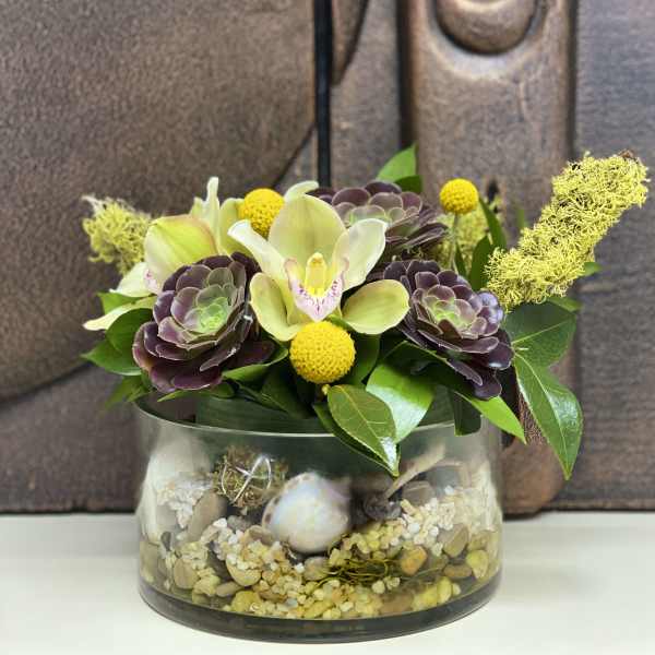 Succulent arrangement with orchids and yellow pom-pom flowers in a glass bowl