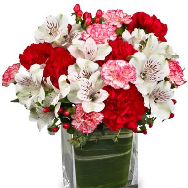 Bouquet of red and pink flowers in a square glass vase