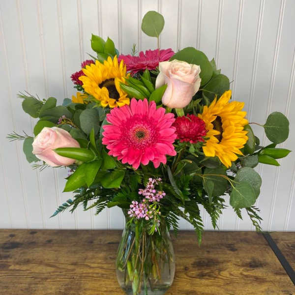 Mixed bouquet of pink, yellow, and pale roses in a glass vase