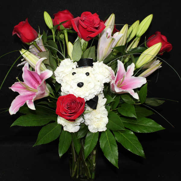Bouquet of red roses and pink lilies with a white teddy bear in a vase