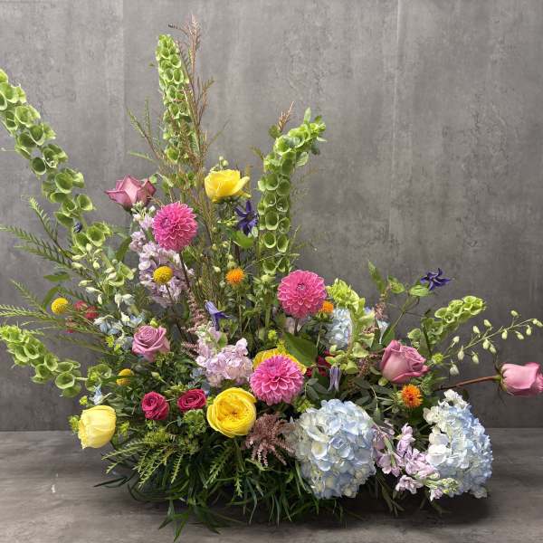 Large mixed floral arrangement with pink, yellow, blue, and green blooms