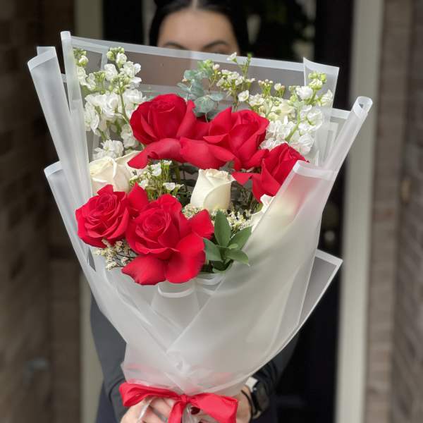 Bouquet of red and white roses wrapped in white paper with a red ribbon