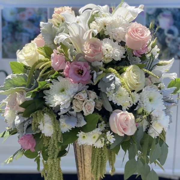 Large pastel floral arrangement in a tall urn vase