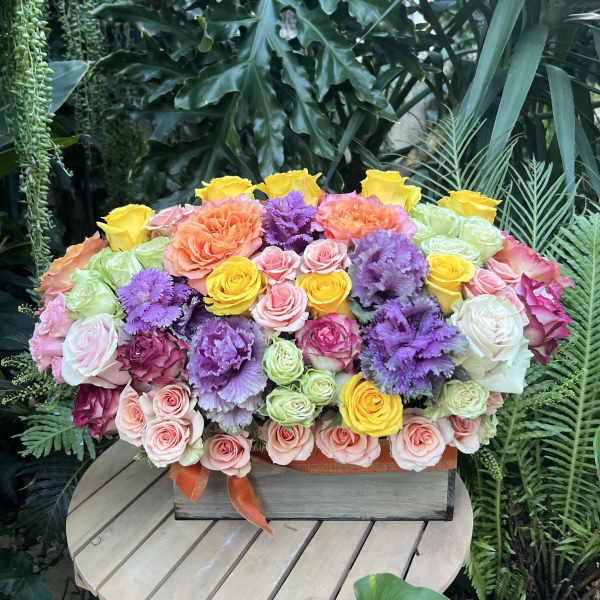 Mixed bouquet of roses and purple ornamental blooms in a wooden box